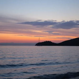 Coastal scene with a sailboat anchored near an island